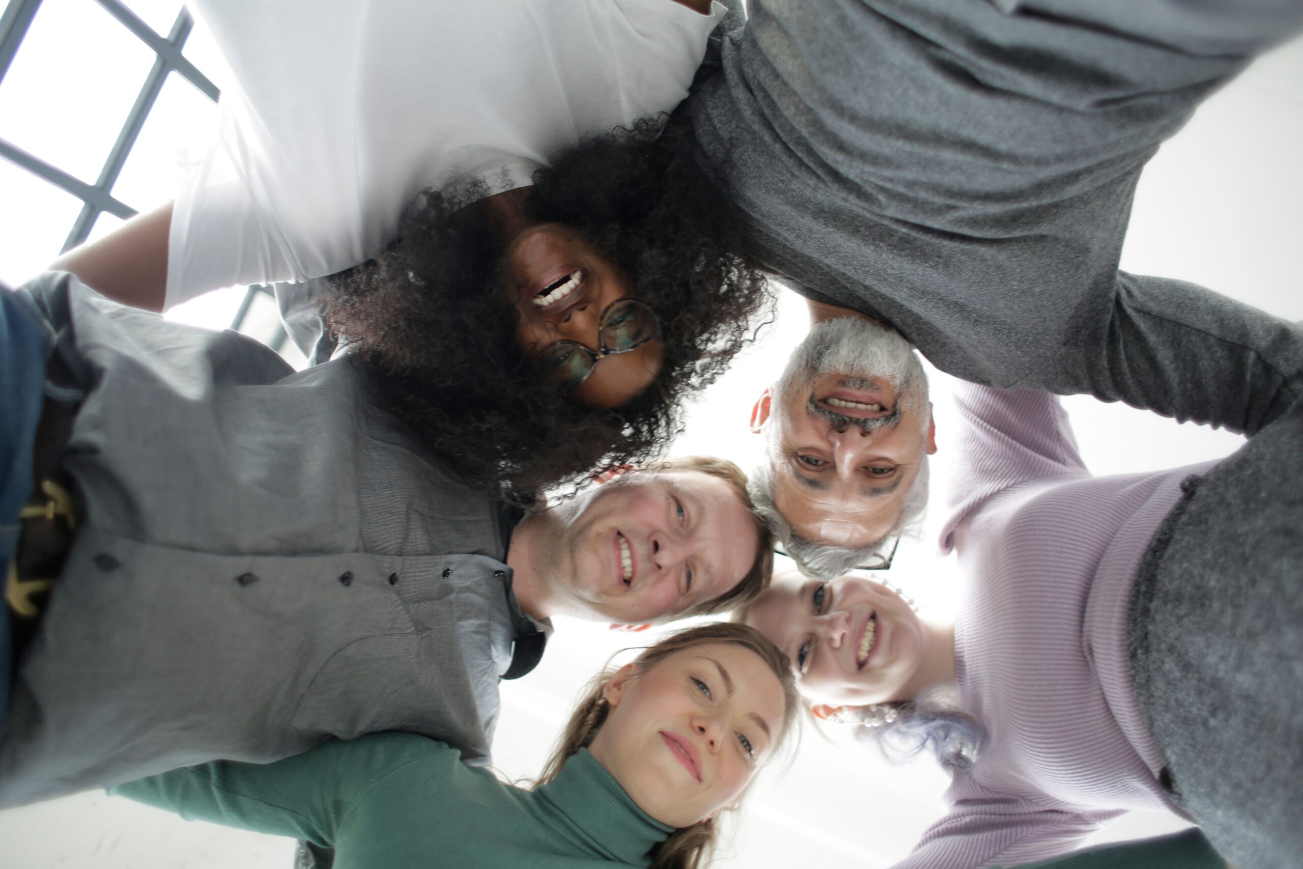 Gruppo di persone di età e percorsi diversi in conversazione in un ambiente luminoso, a rappresentare la varietà di profili che scelgono la professione di Professional Organizer