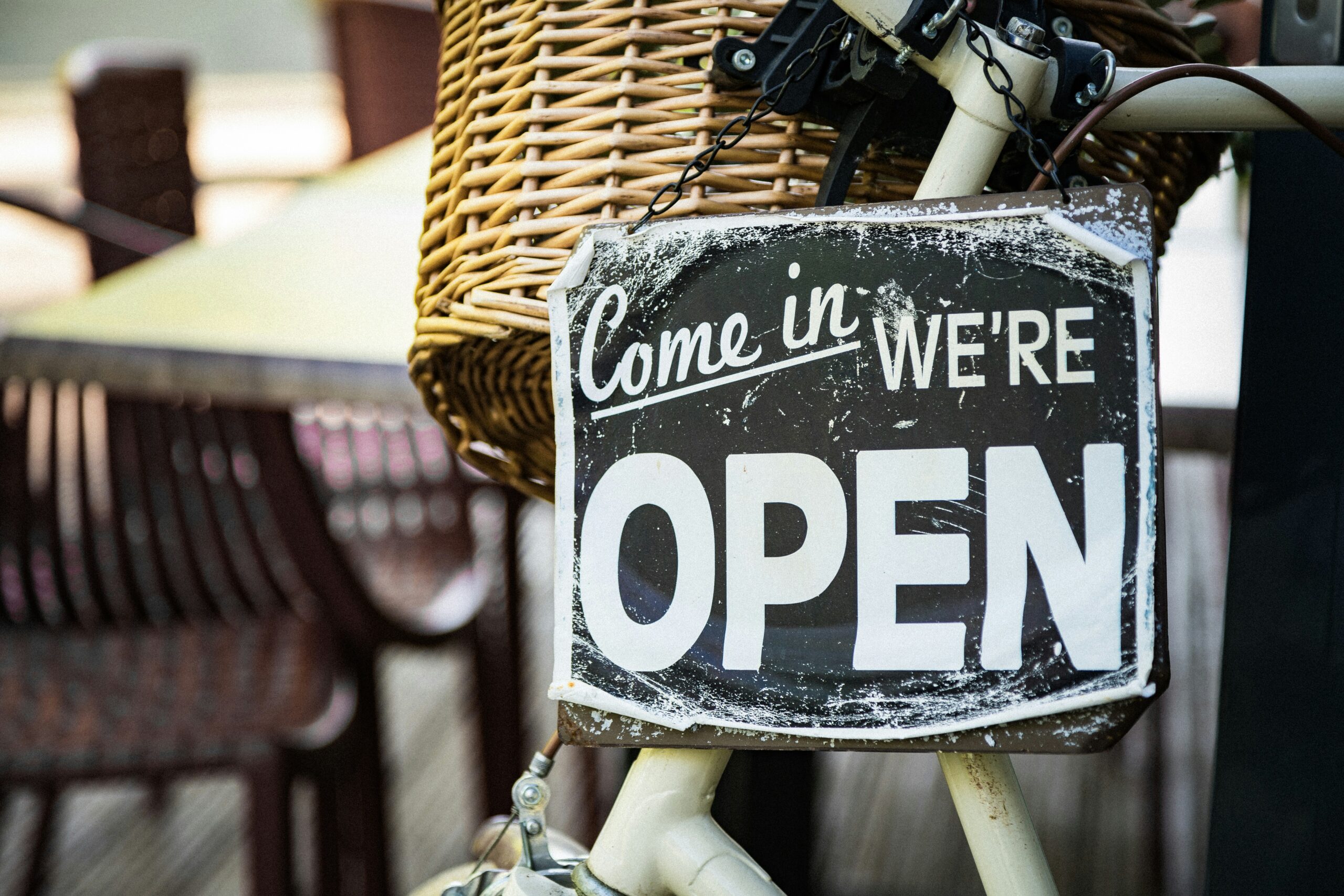 Cartello "Come in, We're Open" appeso alla bicicletta — l'immagine di chi apre la propria attività e inizia ad accogliere i primi clienti