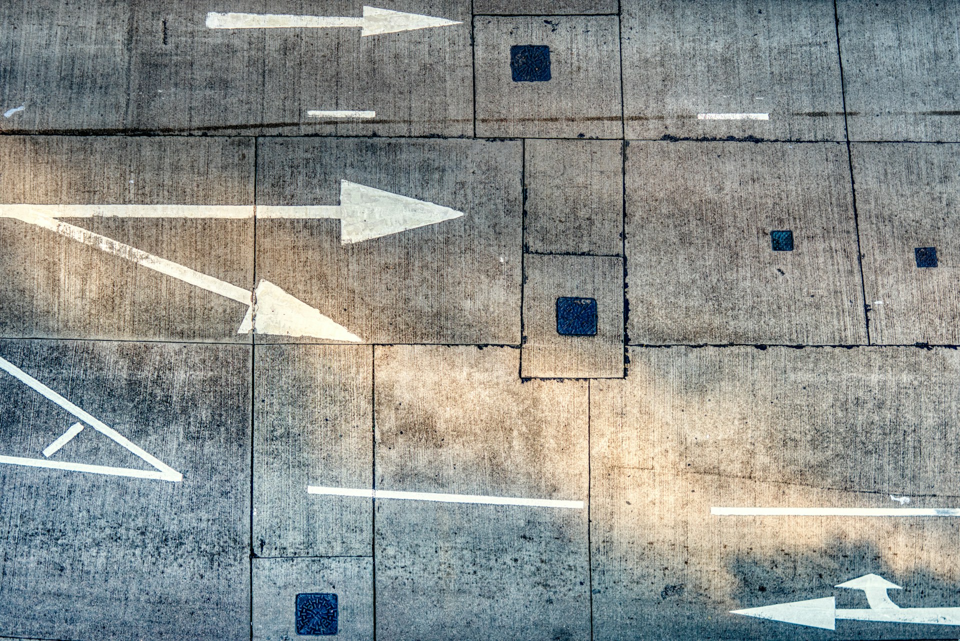 Frecce dipinte sull'asfalto in direzioni diverse — l'immagine di chi deve scegliere quale percorso prendere per diventare Professional Organizer